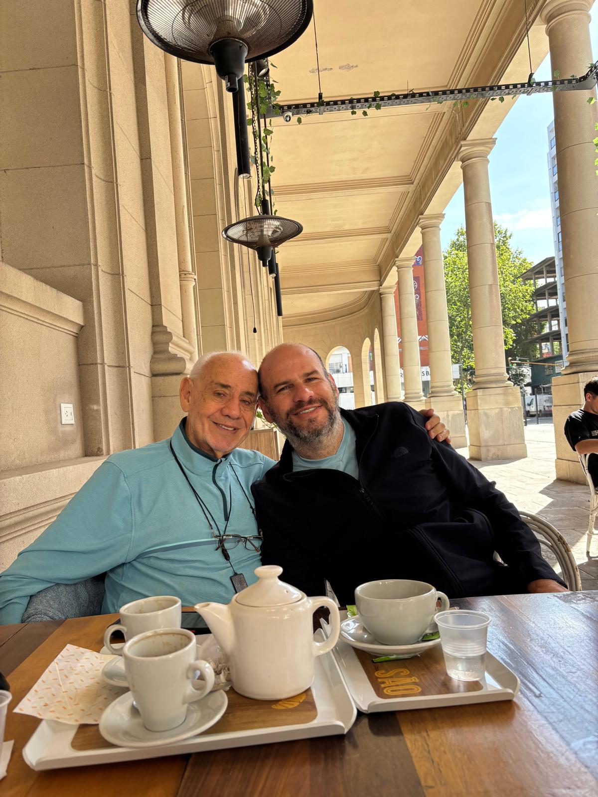 Mario con suéter azul y Mauro con suéter negro, juntos durante una reunión en un café